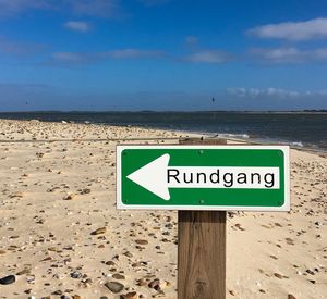 Information sign at beach against blue sky