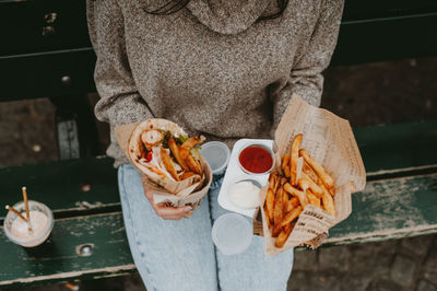 Midsection of women holding food while standing on a public area