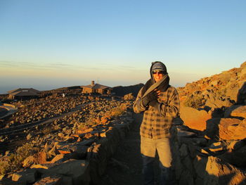 Portrait of man wearing shawl on rocky mountain against sky