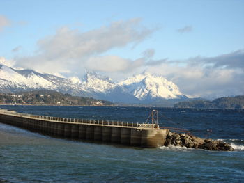 Scenic view of sea by mountains against sky