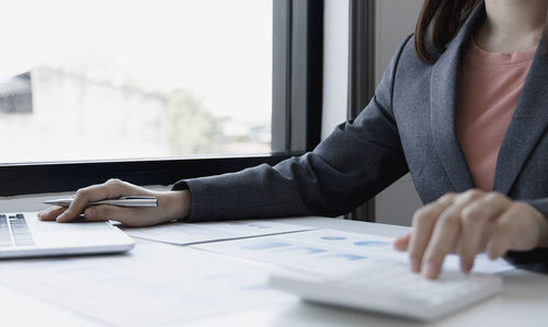 Midsection of woman using laptop on table