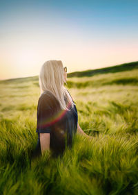 Woman standing in wheat field at sunset