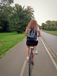 Rear view of woman riding bicycle on road