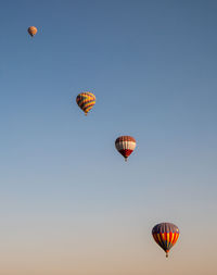 Low angle view of hot air balloons flying against clear sky