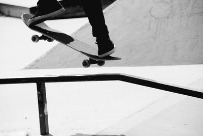 Low section of person skateboarding on sports ramp during sunny day