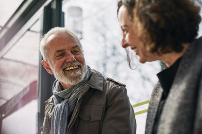 Smiling man talking to woman at bus stop