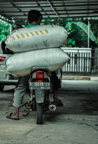 Rear view of man sitting on sidewalk