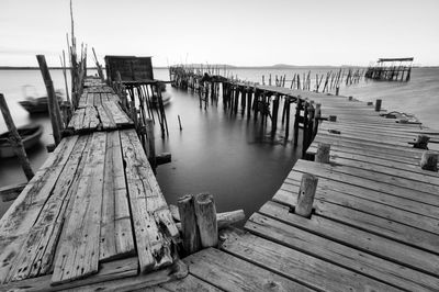 Wooden jetty on pier by sea against clear sky
