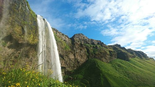 Low angle view of skogafoss waterfall against sky