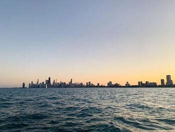 Scenic view of sea and buildings against sky during sunset