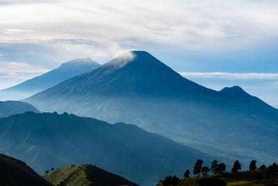 Scenic view of snowcapped mountains against cloudy sky