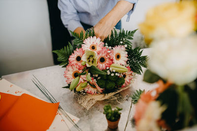 Midsection of man holding flower bouquet on table