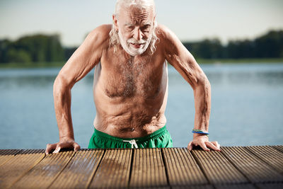 Portrait of senior man leaning on jetty at lake