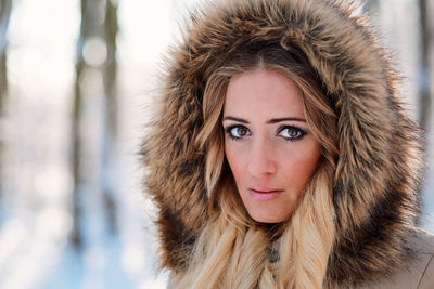 Portrait of young woman wearing warm clothing standing in forest