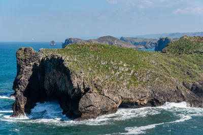 Rock formation on sea shore against sky