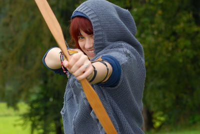 Portrait of woman aiming arrow while standing on land