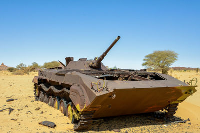 Abandoned truck on field against clear blue sky