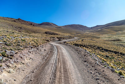 Road amidst field against clear sky