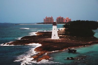 Lighthouse by sea against clear sky