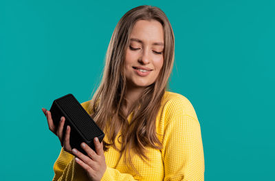 Portrait of young woman using mobile phone against clear blue background