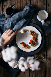 Cropped hand having food with fork in home