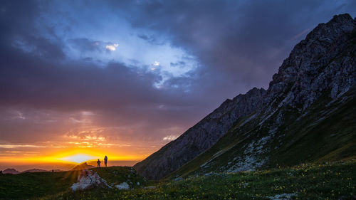 Distant view of people on mountain against cloudy sky