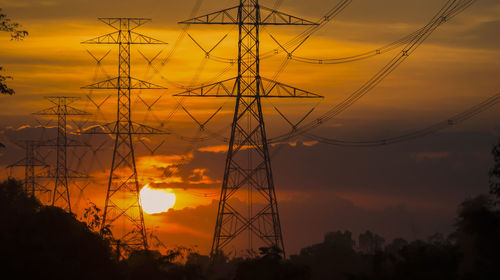 Silhouette electricity pylon against romantic sky at sunset