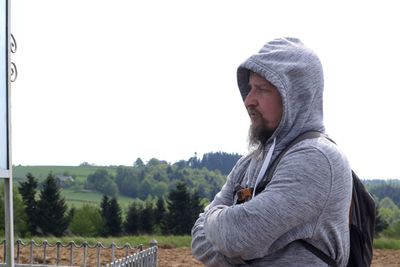 Side view of man looking away on field against clear sky