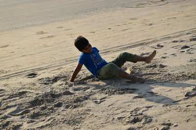 Rear view of boy playing on sand at beach