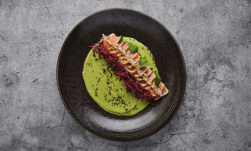 Close-up of savory japanese salmon tataki dish topped with sesame and served with crispy strips. 