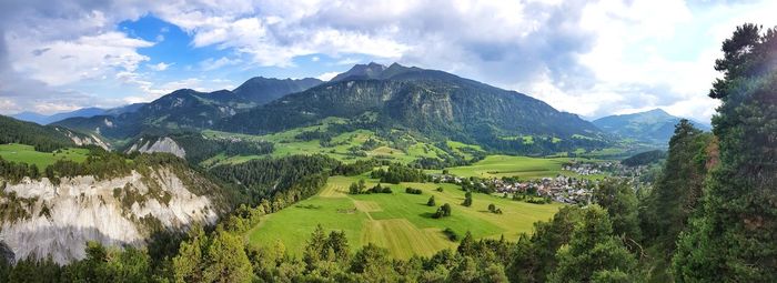 Panoramic view of green landscape and mountains against sky
