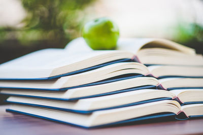 Granny smith apple on open stacked books at home