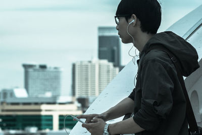 Young man with arms outstretched standing in city