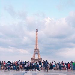 Group of people visiting tower against cloudy sky