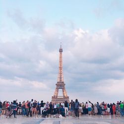 Group of people visiting tower against cloudy sky