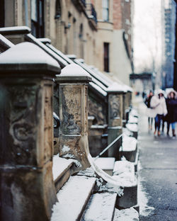 Snow covered steps against buildings in city