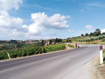 Group of people on road in city against sky