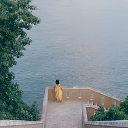 High angle view of woman standing by railing against sea