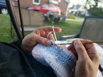 Midsection of person knitting while sitting in yard