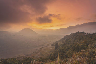 Scenic view of mountains against cloudy sky during sunrise