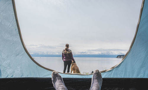 Rear view of woman sitting on boat sailing in sea against sky