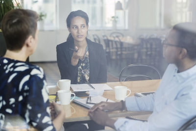 Businesswoman discussing with colleagues at conference table