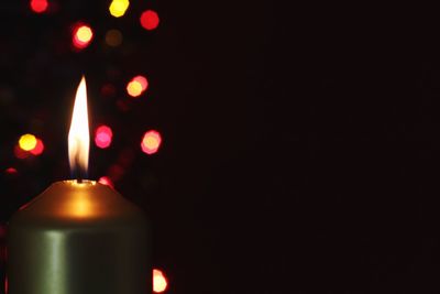 Low angle view of lit candle in darkroom