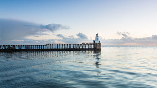 Pier over sea against sky during sunset