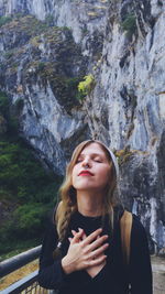 High angle view of young woman with eyes closed standing against mountain