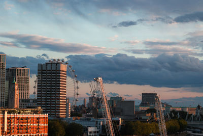 Modern buildings in city against sky during sunset