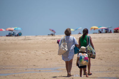 Rear view of friends walking on beach