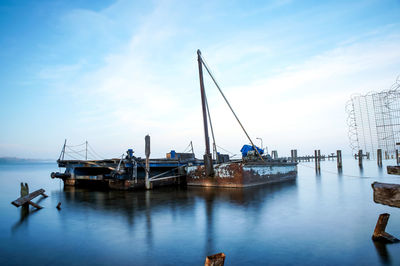 Boats moored at harbor against sky