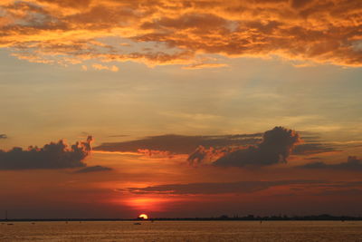 Scenic view of sea against cloudy sky during sunset