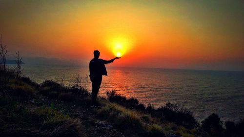 Silhouette man standing on beach during sunset